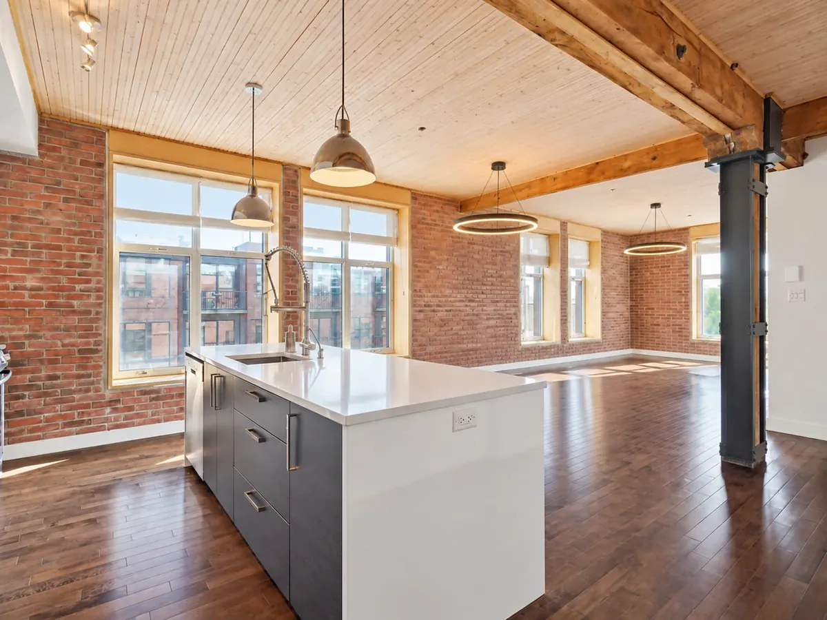 Intérieur d'un loft du 373, rue des Seigneurs : mur de brique, poutres de bois et plafond de planches