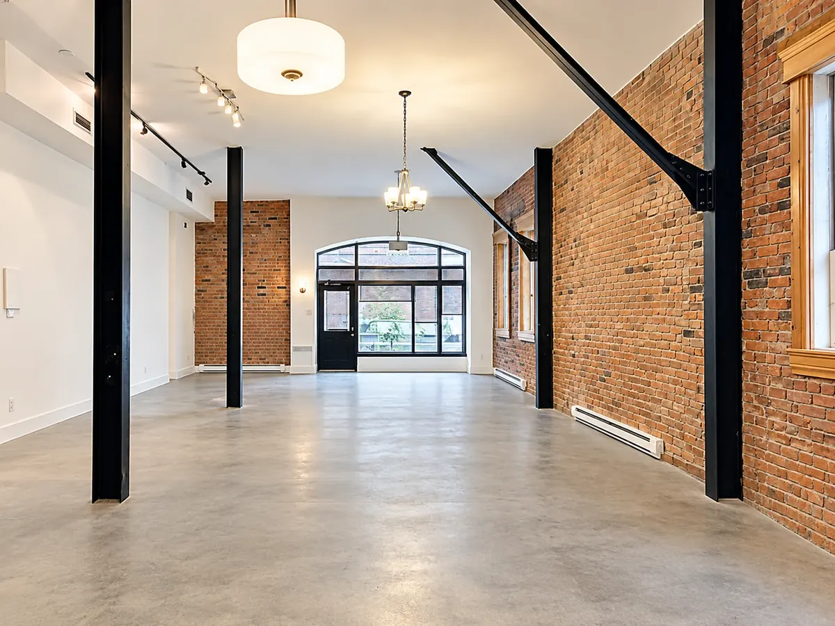 Intérieur d'un espace du Belvédère : mur de brique, colonnes d'acier et plancher de béton poli