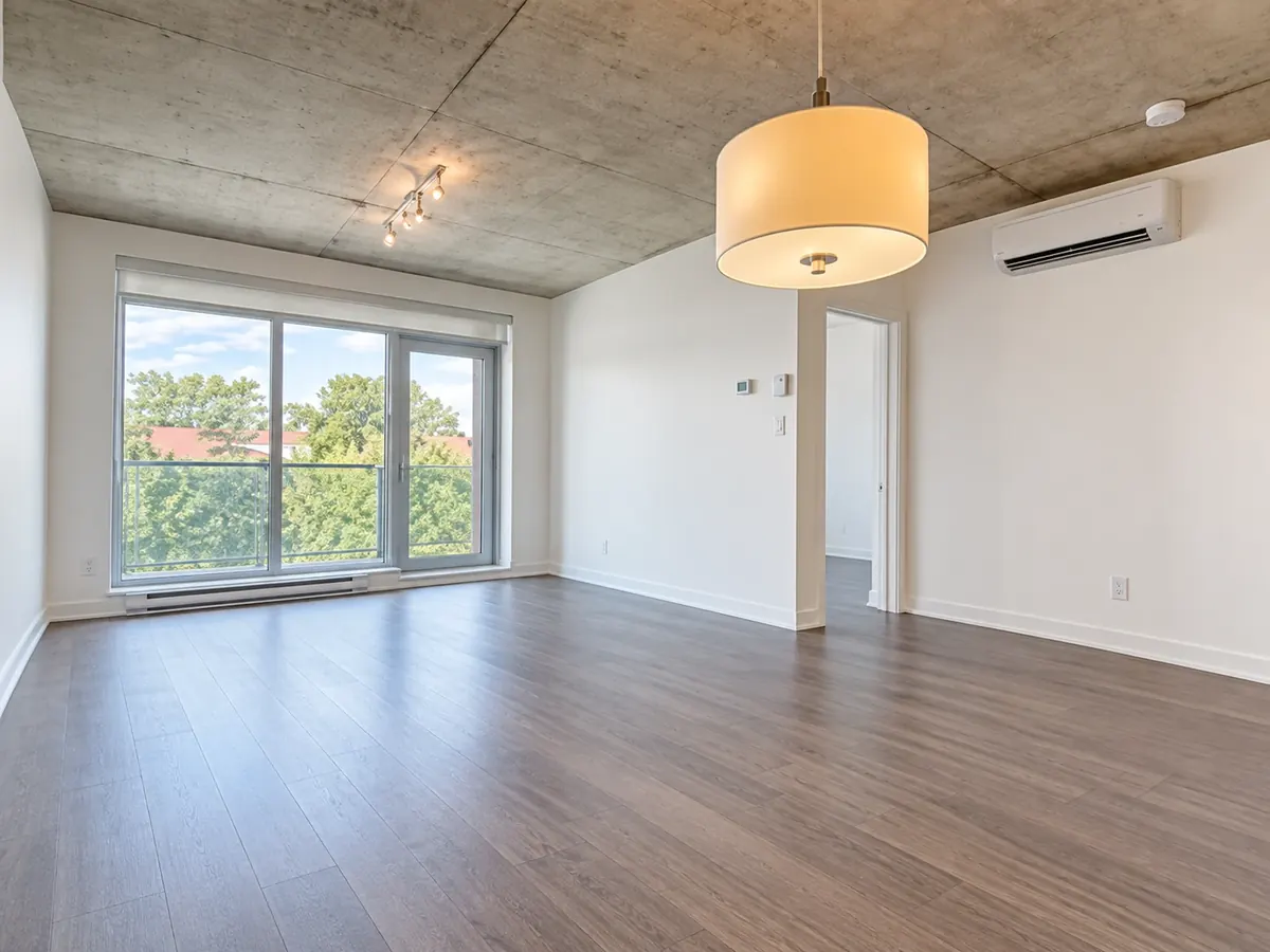 Intérieur d'une unité des Lofts Angus : plafond de béton, fenêtre sur la rue et plancher gris