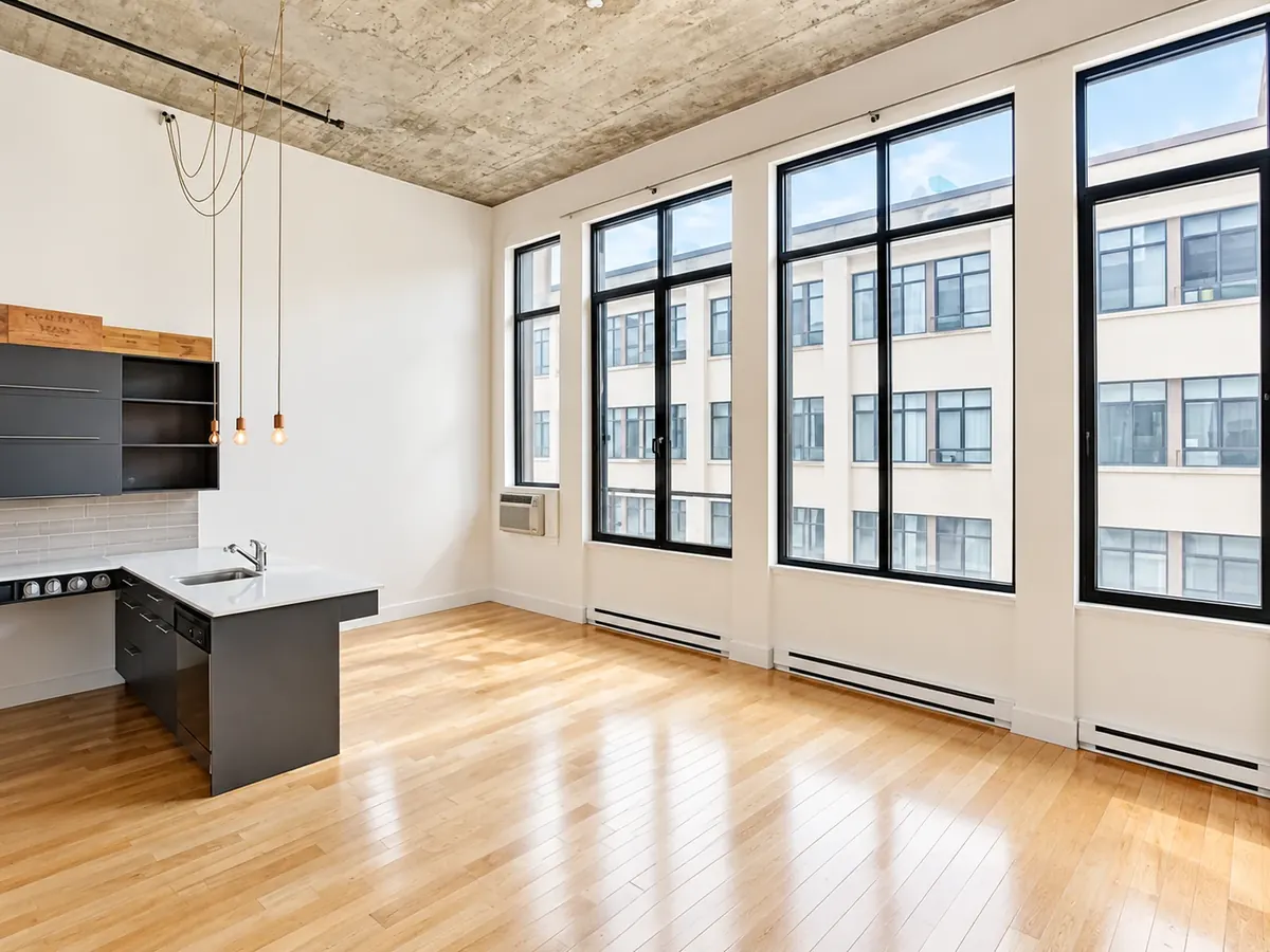 Intérieur d'un loft des Lofts Impérial phase 3 : plafond de béton, fenêtres à cadres noirs et plancher d'érable