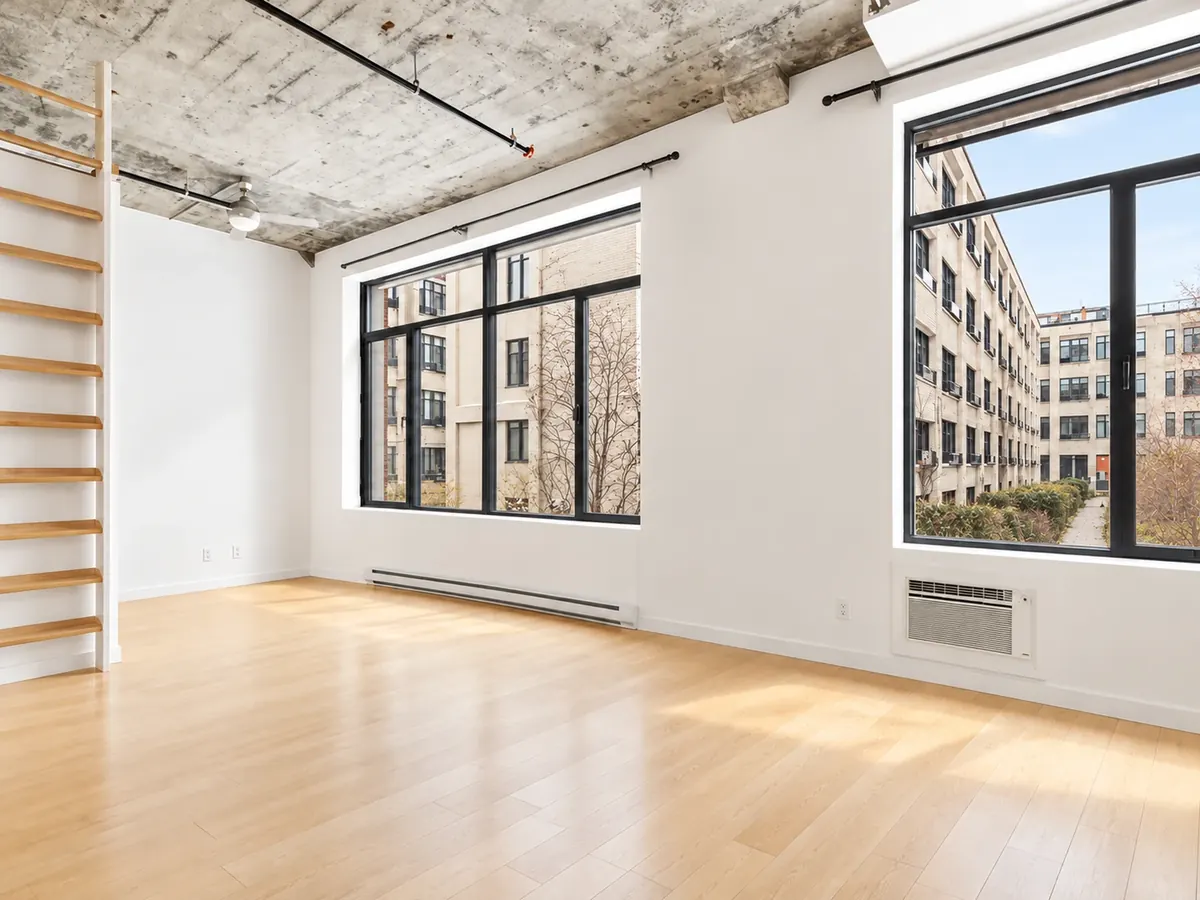 Intérieur d'un loft des Lofts Impérial phase 4 : plafond de béton, fenêtres à cadres noirs et plancher de bois blond