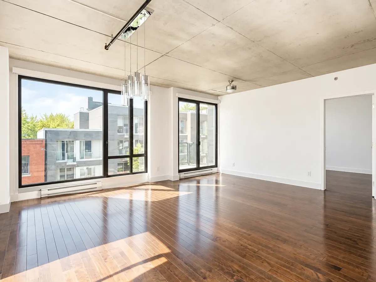 Intérieur d'un loft des Lofts Impérial phase 6 : plafond de béton, grande fenêtre et plancher de bois