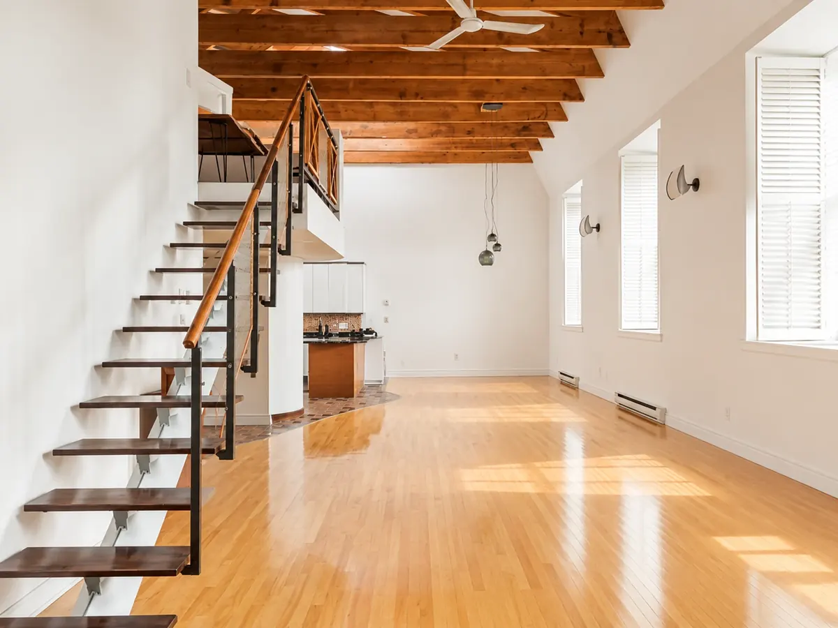 Intérieur d'une unité du Mont-St-Louis : escalier à marches de bois et plafond à poutres de bois